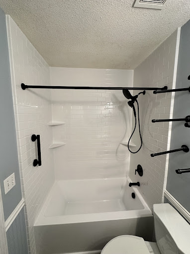 A white toilet sitting next to a white bath tub